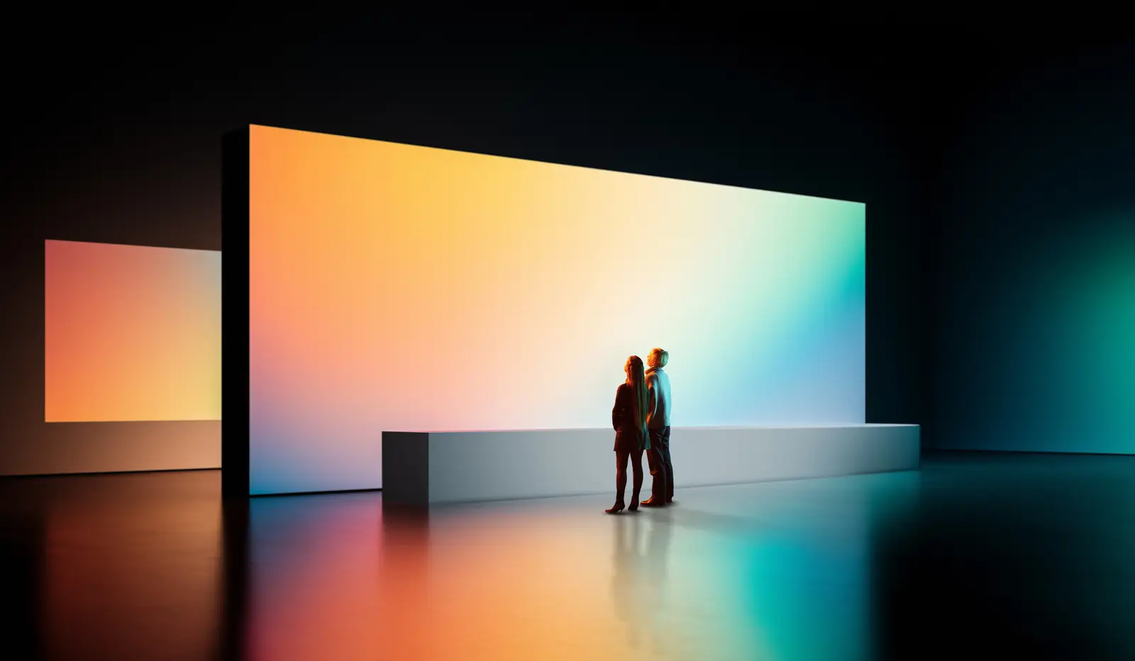 Two people standing before a wide, glowing gallery wall